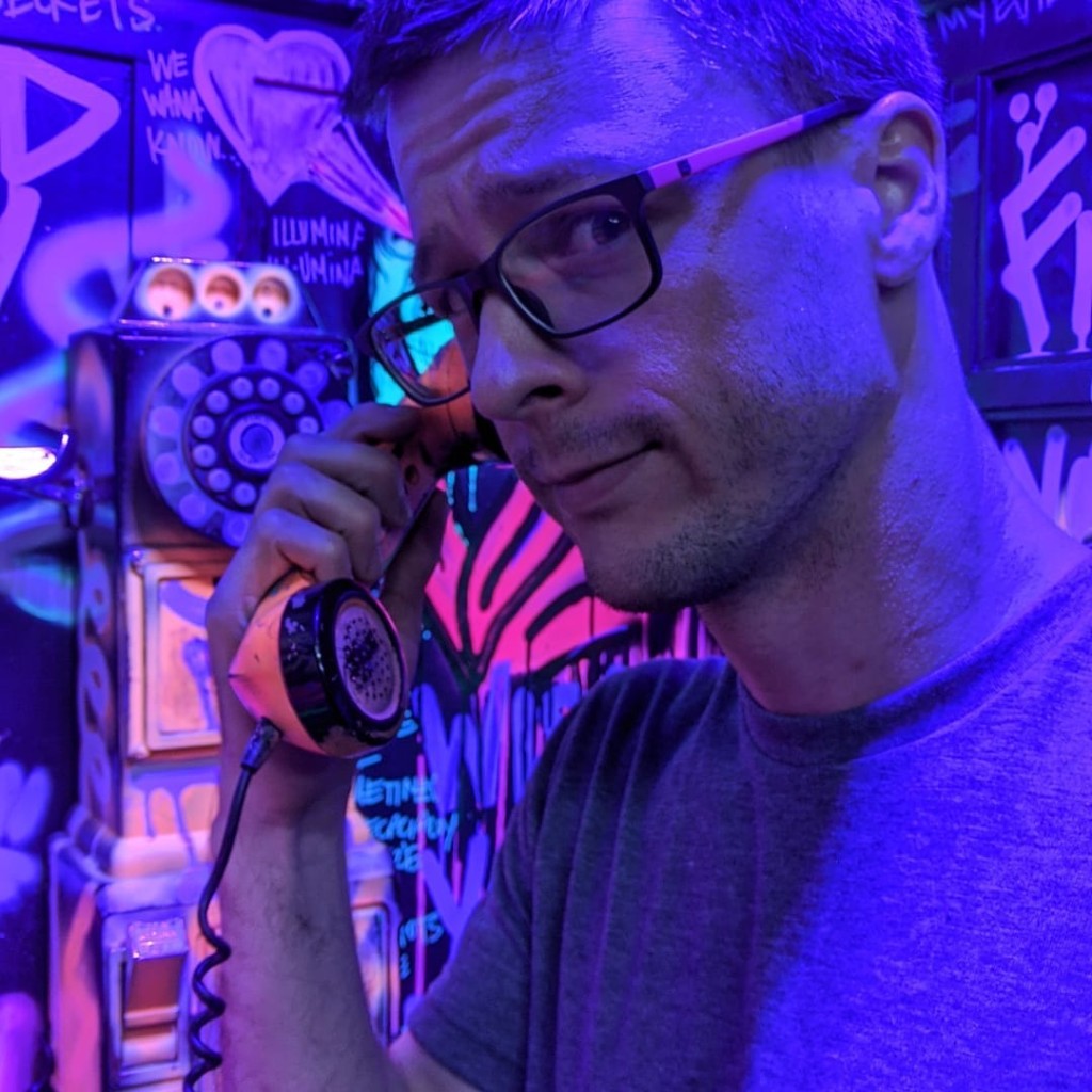 Portrait with a payphone receiver, neon blue and purple light, graffiti wall behind